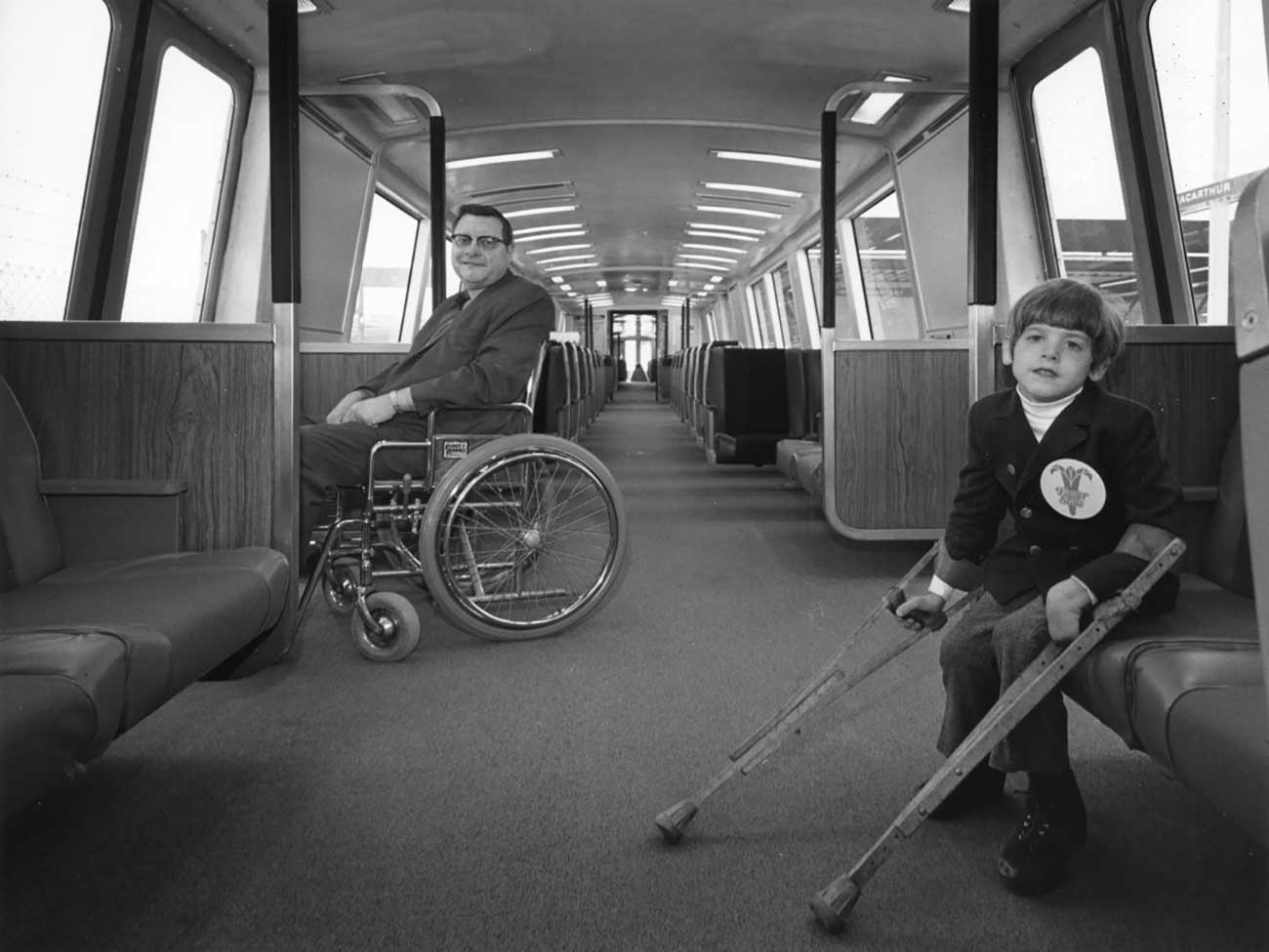 A young boy on crutches and man in a wheelchair on a BART train.
