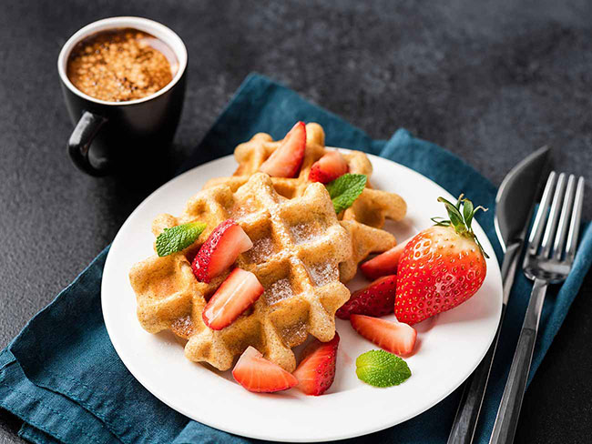Homemade waffles topped with fresh strawberries.